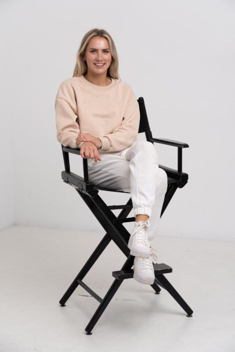 Fashion Photographer North Shore Blond Woman wearing a cream outfit sitting of a black chair