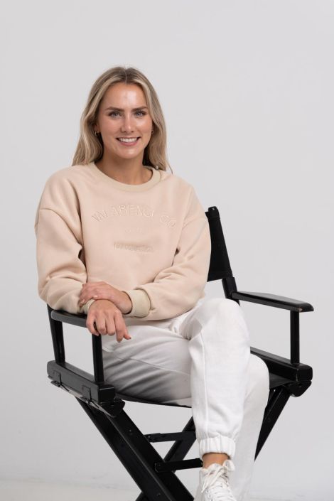 Fashion Photographer North Shore Studio lookbook photography for New Zealand apparel brand: Blond Woman wearing a cream outfit sitting of a black chair
